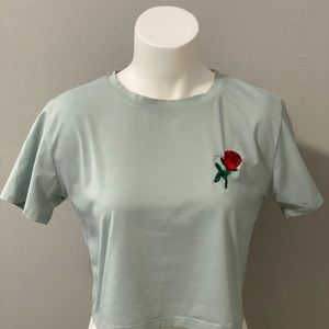 Green crop top with rose embroidery on upper side.